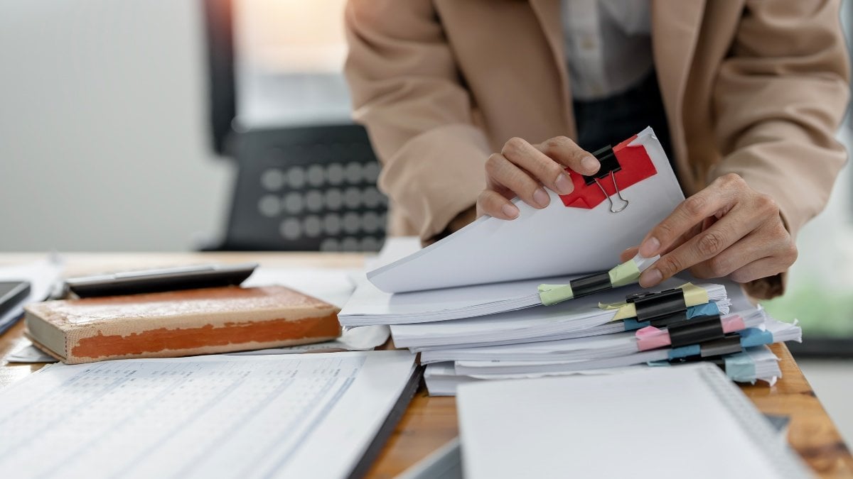Businesswoman hands working on Stacks paper document files on her desk.