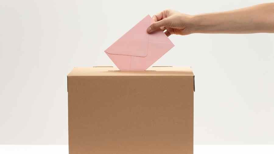 hand-puts-pink-envelope-into-vote-box (1)