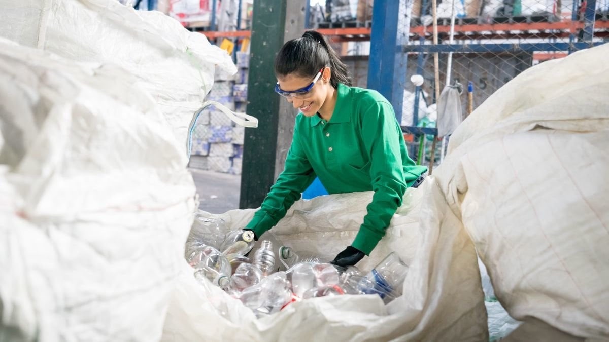 Woman working in a recycling factory sorting some bottles and looking very happy - environmental concepts