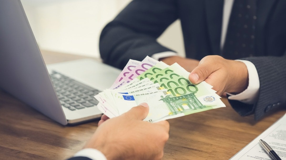Businessman giving money, Euro banknotes, to his partner while making contract
