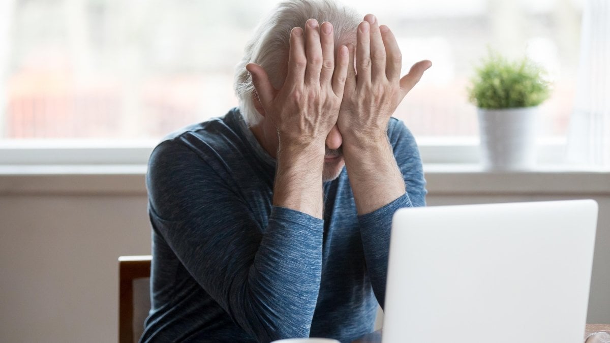 Fatigued senior mature man feels tired from computer rubbing dry irritated eyes to relieve pain or crying frustrated upset, old middle aged male suffering from eyestrain after long laptop use concept