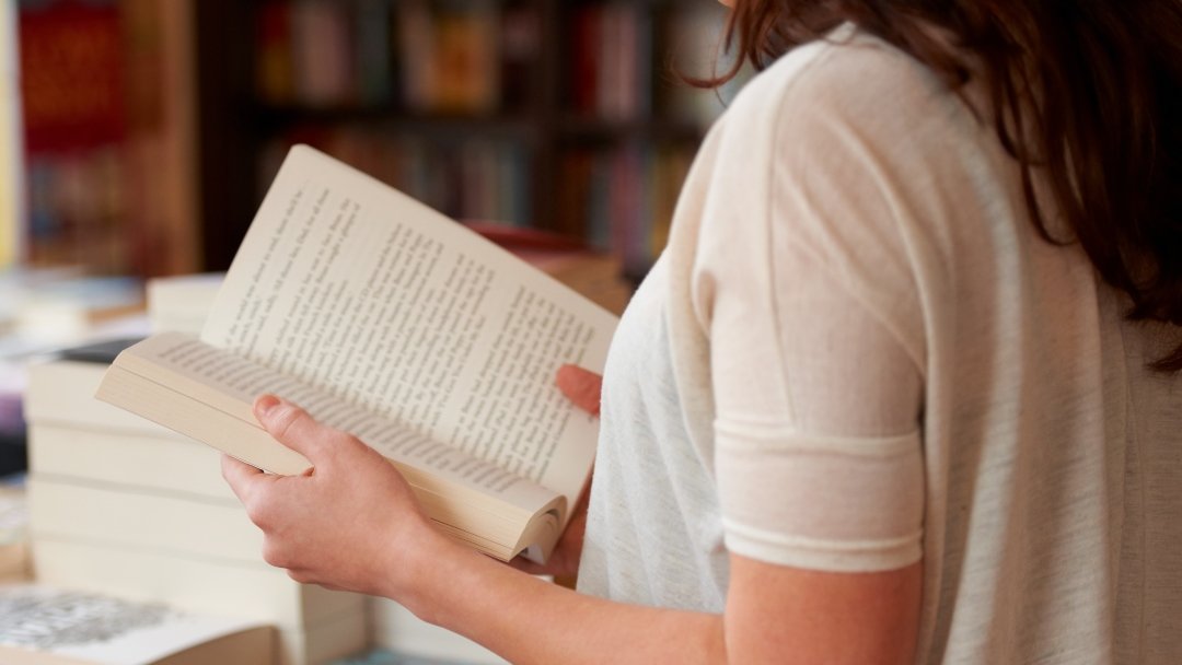 perdido-paginas-captura-recortada-mujer-joven-que-lee-libro-mientras-pie-libreria