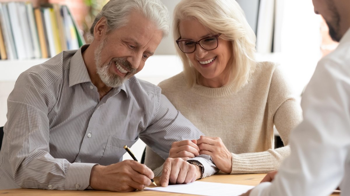 Happy older family couple clients make sale purchase deal sign insurance contract meeting estate agent lawyer bank manager, satisfied senior customers make business financial deal buy house take loan