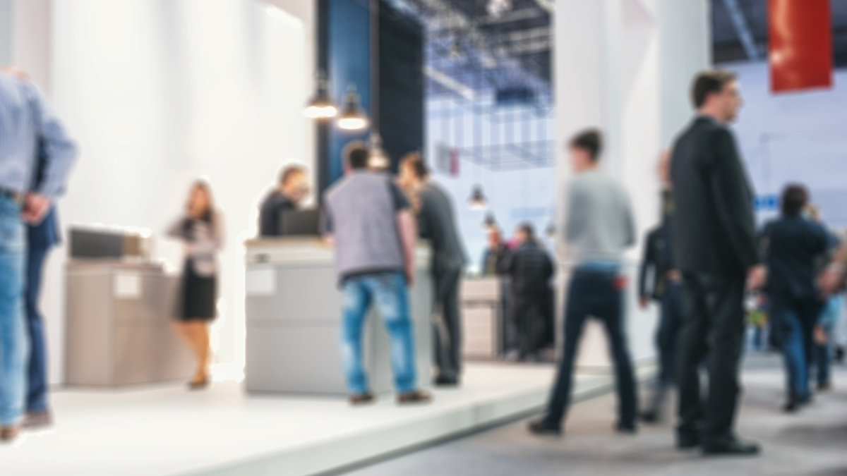 blurred people standing and walking on a trade show booth. ideal for websites and magazines layouts