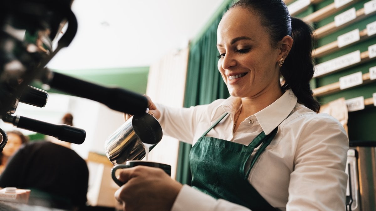 Caucasian female barista at work making coffee, close up
