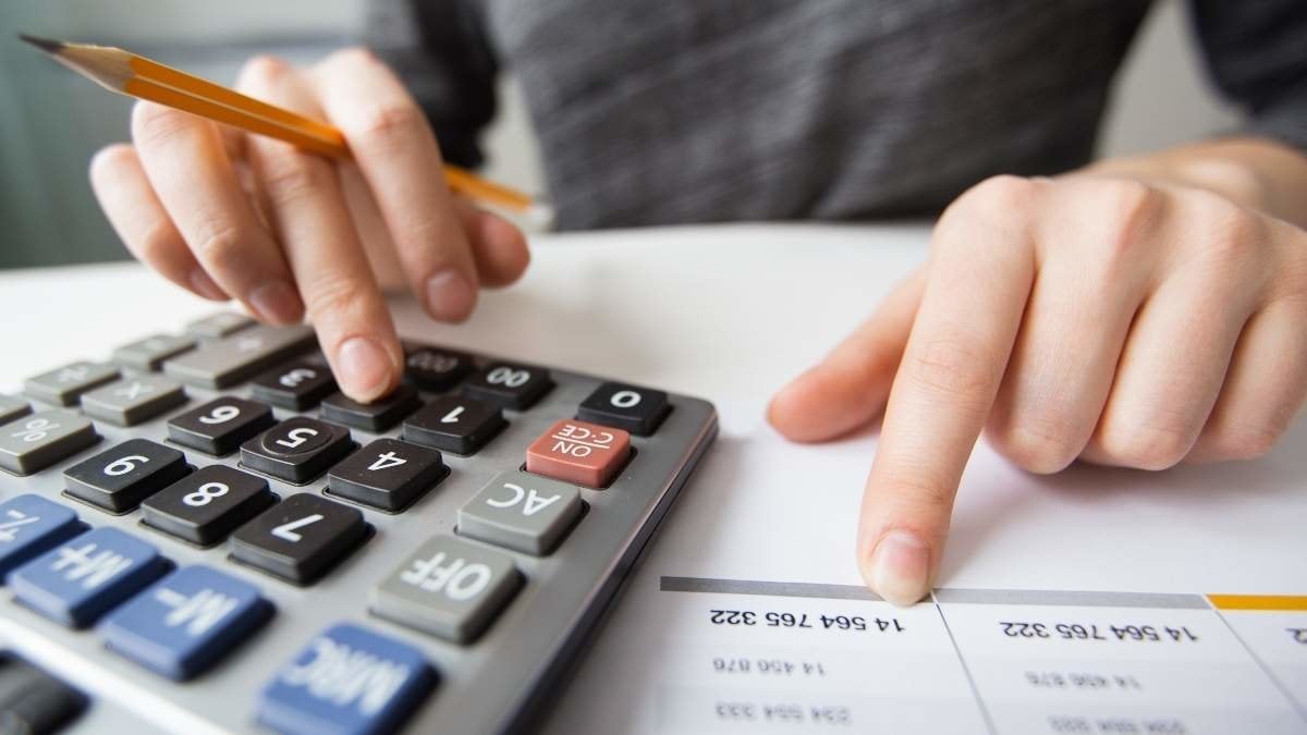 Closeup of accountant counting on calculator and working with table