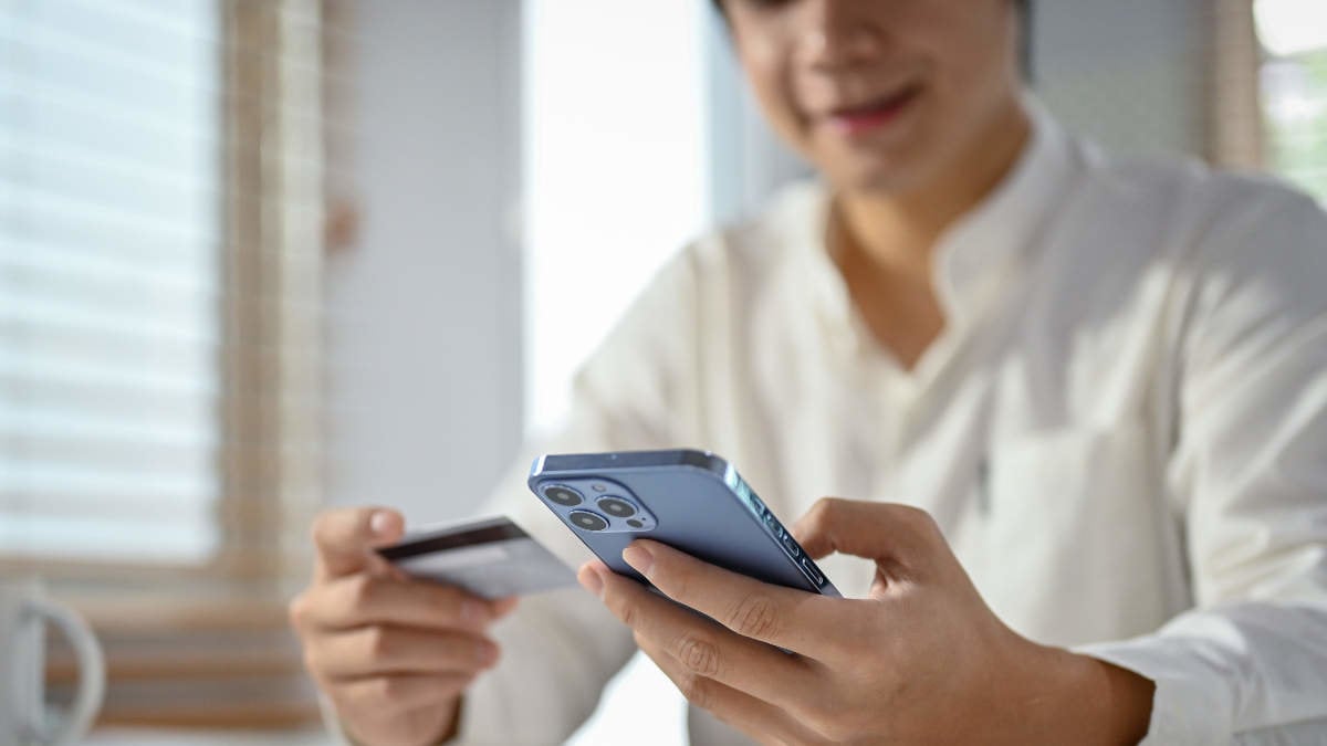 Close-up and selective focus image, An Asian man using mobile banking application to transfer money or pay online shopping bills.