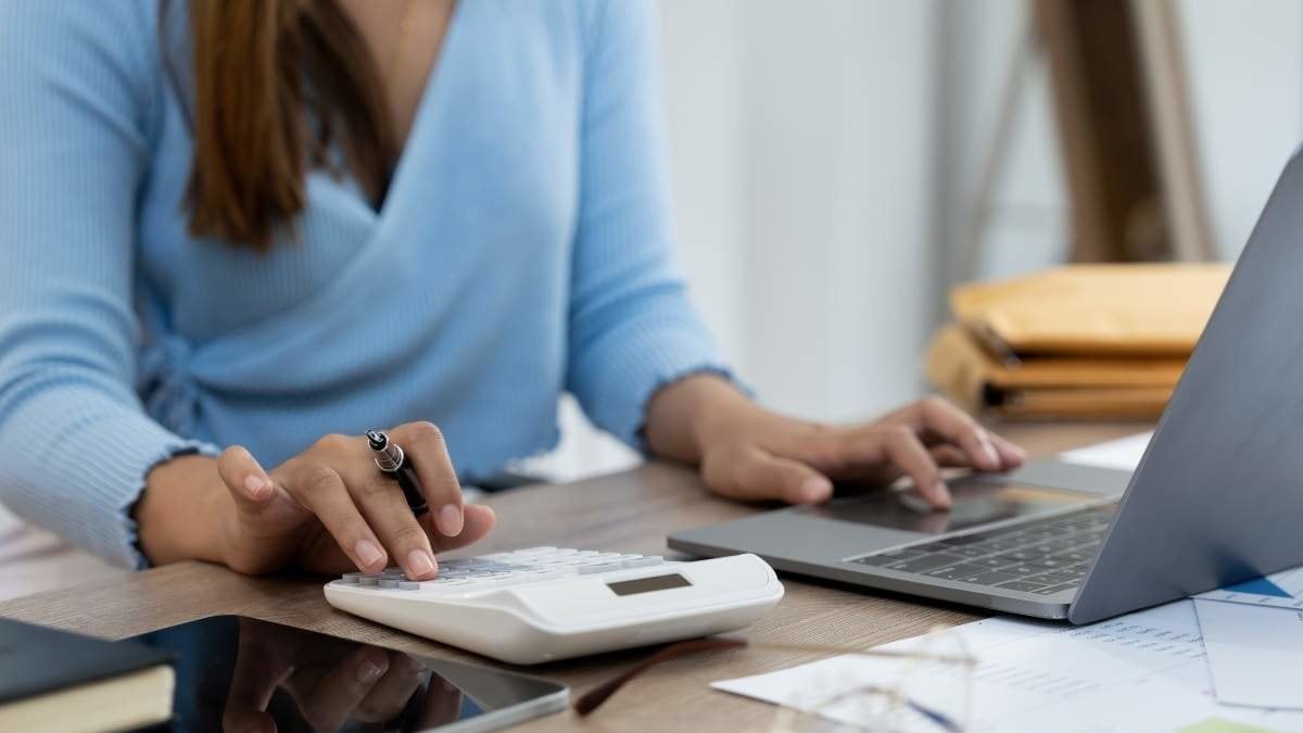 Woman hand holding pen and using calculator with doing finance on desk at home office.
