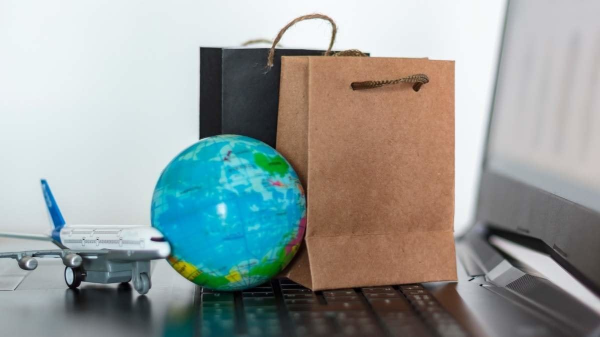 Shopping bags with world globe and airplane on laptop. Worldwide online shopping concept