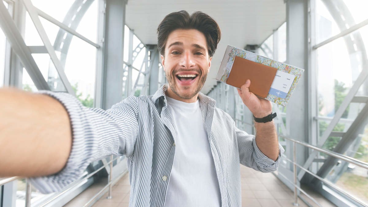 I'm going to trip! Excited guy taking selfie with passport and tickets at airport