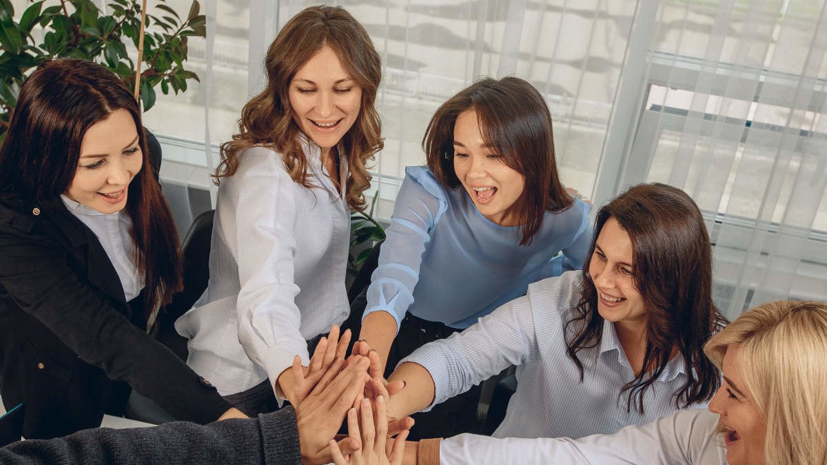 Top view of smiling cheerful team of office workers holding hands as a sign of support and leadership relationship. Job success concept