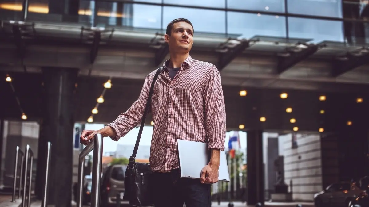 Guy on the modern street in casual clothing with laptop