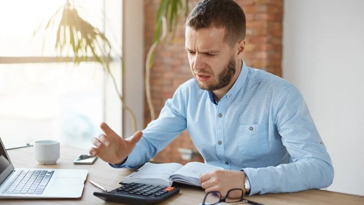 Portrait of unhappy mature bearded accountant working in company office, being frustrated calculating profits one more time because of mistake. Business concept