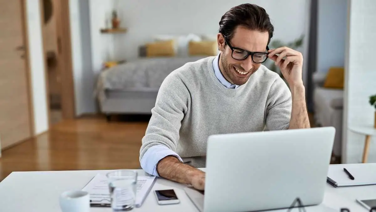 Young happy businessman working on laptop at home.