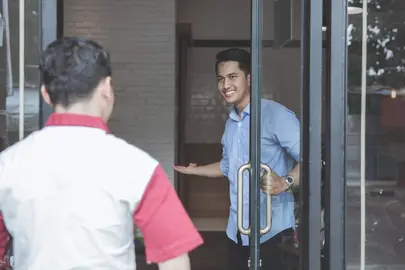 Confident young barber expert smiling welcoming customer to his barbershop