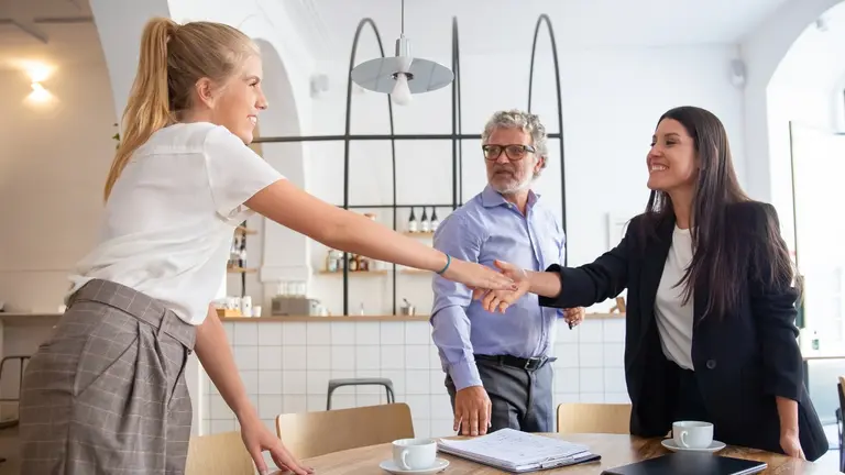 Successful female business professional meeting with customers and shaking hands. Man and women in co-working space. Partnership or business meeting concept