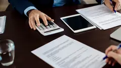 Close-up of real estate agent calculating costs of a mortgage agreement while having a meeting with a client in the office.