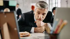 Pensive businessman feeling tired of work and contemplating while sitting at desk in the office.