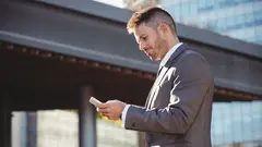 Businessman using mobile phone near office building