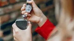 Stylish girl in a city. Lady use the electronic cigarette. Woman in a red jacket.