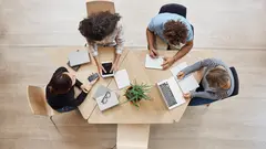 View from above. Business,startup, teamwork concept. Startup partners sitting at coworking space talking about future project, looking through examples of work on laptop and digital tablet