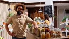 Portrait of smiling man looking for farm grown vegetables in eco friendly zero waste store. Hipster client does grocery shopping, buying vegan food in environmentally friendly local neighborhood store