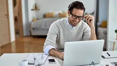 Young happy businessman working on laptop at home.